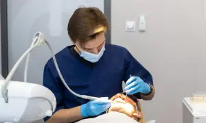 Dentysta w masce i rękawiczkach wykonuje zabieg. Znieczulenie komputerowe przeciwwskazania są ważne dla bezpieczeństwa pacjenta.