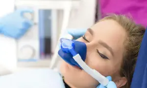 Kobieta z maską gazu rozweselającego na twarzy, przygotowana na wizytę u dentysty. Leki uspokajające pomagają zredukować stres.