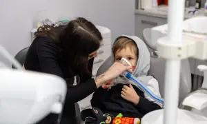 Chłopiec w masce znieczulającej u dentysty. Po zabiegu może pojawić się krwiak po znieczuleniu u dentysty, ale teraz liczy się spokój.