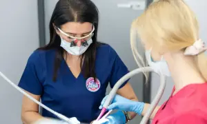 Dentystka w okularach powiększających i asystentka pracują przy pacjencie. Czy znieczulenie u dentysty jest szkodliwe? Nie, jest bezpieczne.