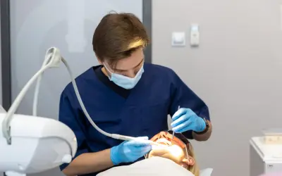 Dentysta w masce i rękawiczkach wykonuje zabieg. Znieczulenie komputerowe przeciwwskazania są ważne dla bezpieczeństwa pacjenta.