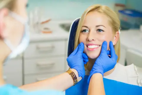 Uśmiechnięta pacjentka z pięknymi zębami, dentysta ocenia estetykę stomatologiczną.