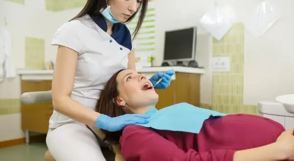 Dentystka bada zęby ciężarnej pacjentki. Bezpieczne wybielanie zębów w ciąży jest możliwe po konsultacji.