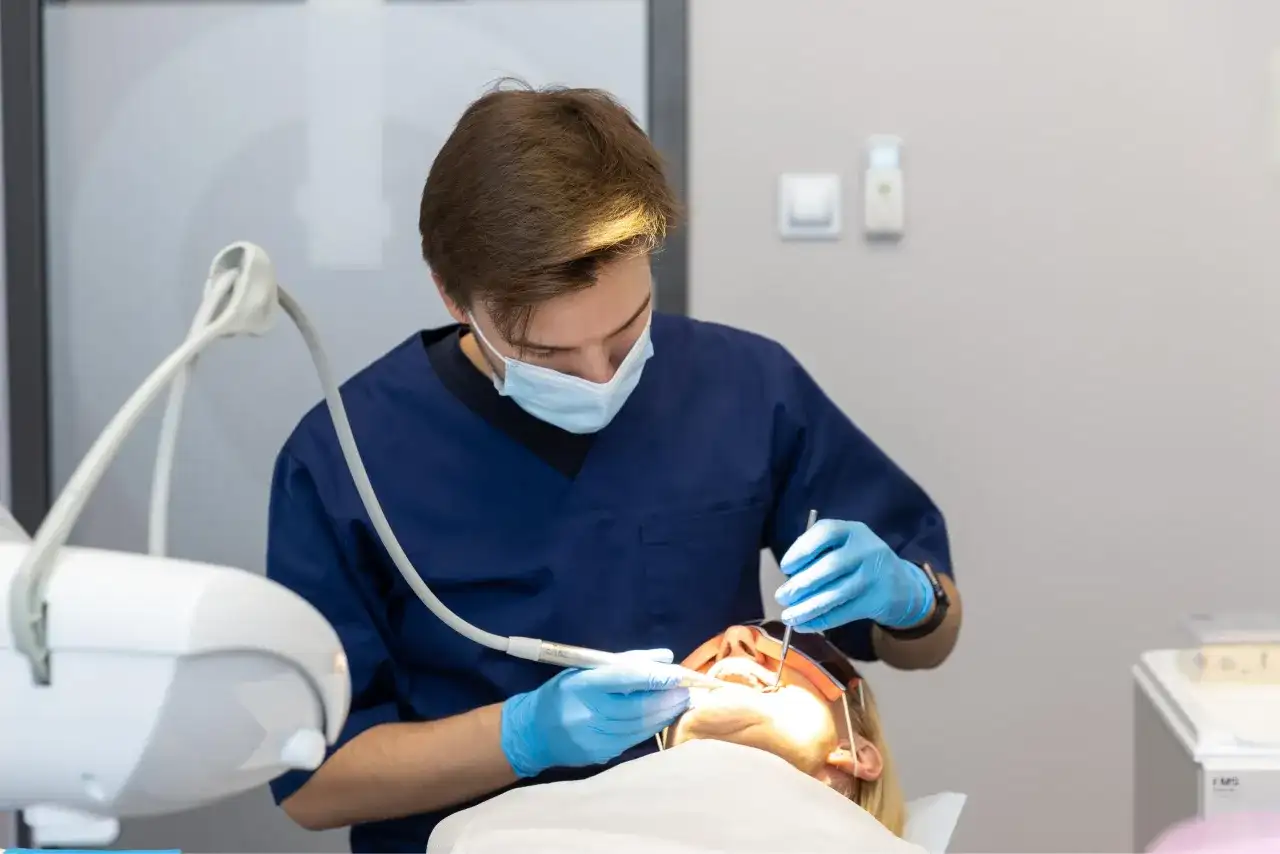 Dentysta w masce i rękawiczkach wykonuje zabieg. Znieczulenie komputerowe przeciwwskazania są ważne dla bezpieczeństwa pacjenta.