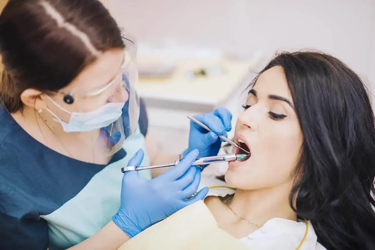 Dentystka podaje znieczulenie pacjentce, pokazując różne rodzaje znieczulenia stosowane w stomatologii.