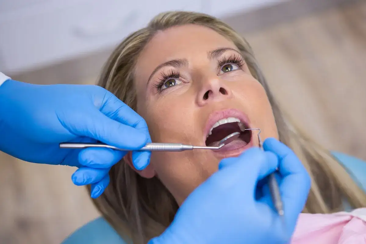Dentysta sprawdza stan tymczasowe licówki na zęby u pacjentki.