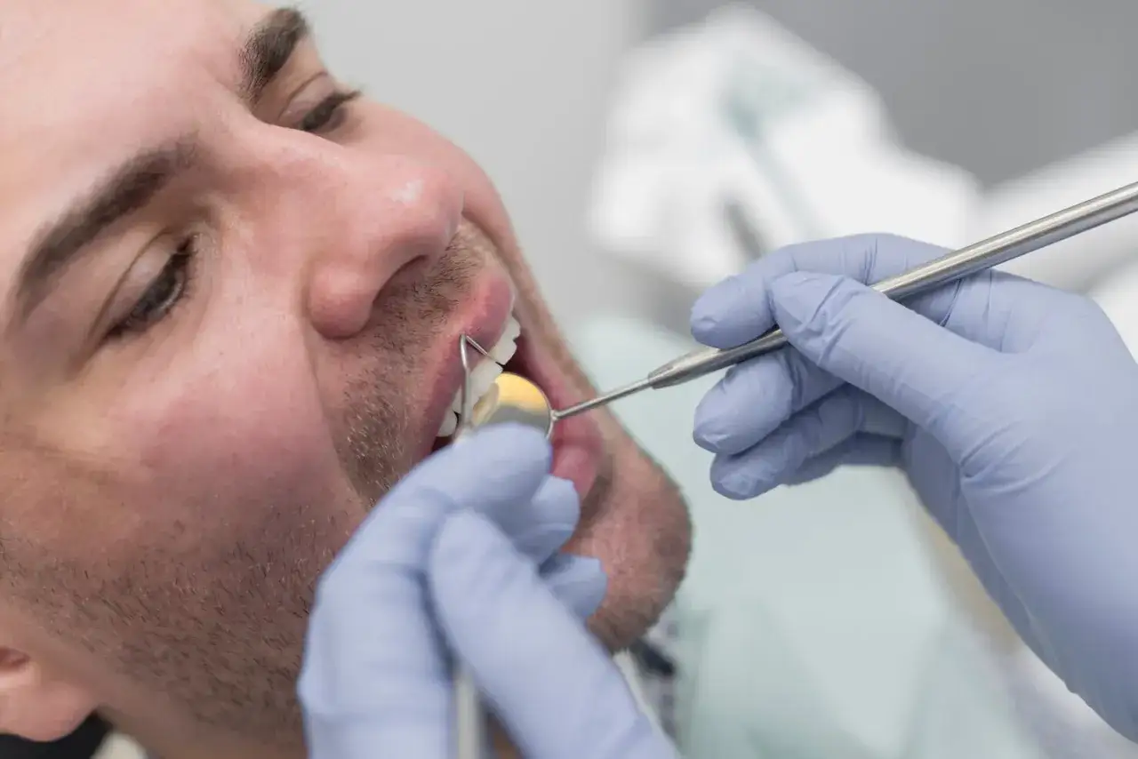 Dentysta bada zęby pacjenta. Pytanie, czy licówki można zdjąć, jest kluczowe dla wielu osób.