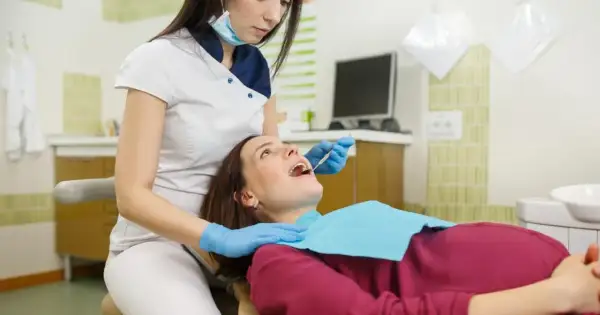 Dentystka bada zęby ciężarnej pacjentki. Bezpieczne wybielanie zębów w ciąży jest możliwe po konsultacji.